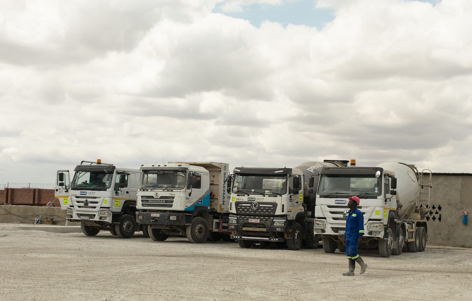 Prevail Concrete fleet lined up in the yard with a crew member
